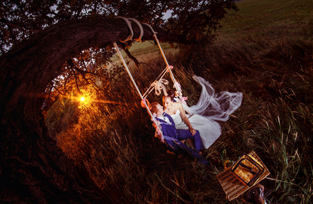 A beautiful married pair is swinging against the field background.の写真素材
