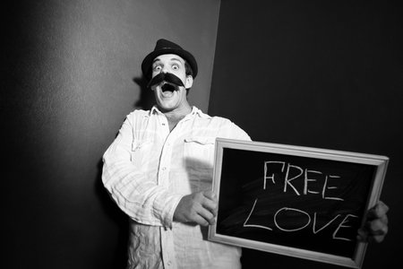 A cheerful man is holding a chalk blackboard with words free love.