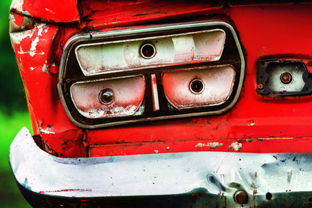Closeup image of vintage rusty red car headlight at green background.の写真素材