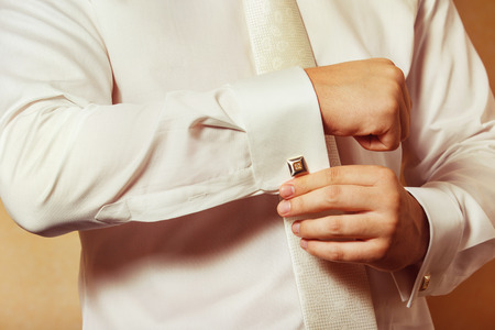 Close-up image of a man in white shirt who fastens a stud. Concept of a young man morning.の写真素材