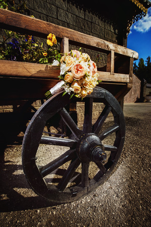 Beautiful pink and white roses wedding flower bouquet at natural wooden cart summer background.の写真素材