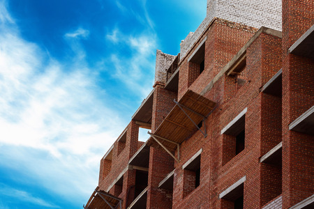 Red bricks building construction at blue cloudy sky background.の写真素材