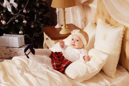 happy baby girl is laughing in bedroom at Christmas tree background.の写真素材