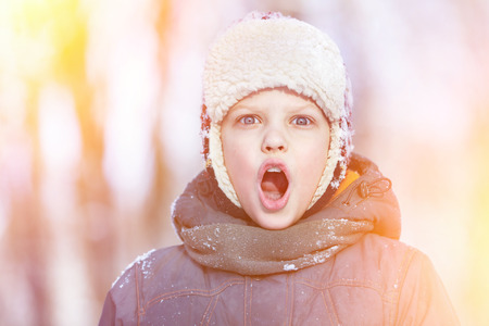 Closeup colorful winter portrait of young shouting boy in hat, scarf and jacketの写真素材