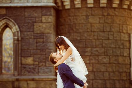 Portrait of beautiful wedding couple having fun at vintage castle with golden sunset background.の写真素材