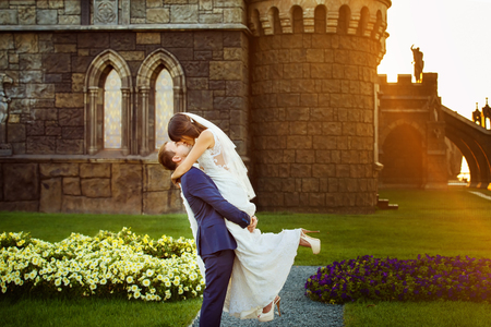 Portrait of beautiful wedding couple having fun at vintage castle with golden sunset background.の写真素材