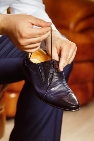 Close up image of a man who is preparing for his workday and tying a shoe lace.の写真素材