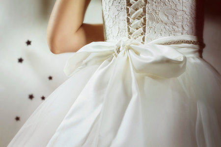 A closeup image of wedding preparations. Bridesmaid is hepling put bride elegant luxury dress.