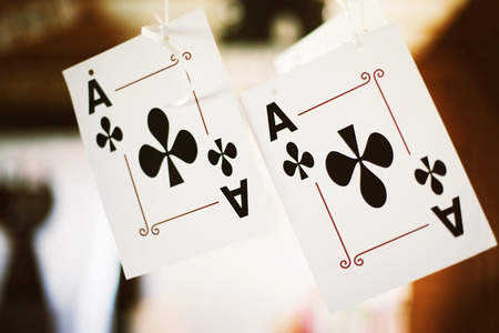 Two clubs aces playing cards are hanging at blurred background.の写真素材