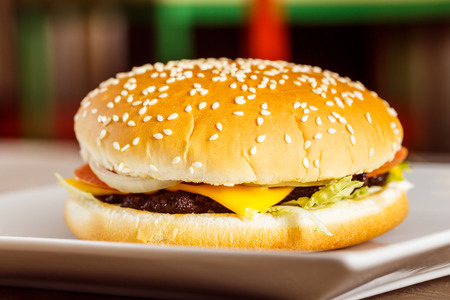 Closeup fresh cheeseburger on white plate at blurred background.の写真素材