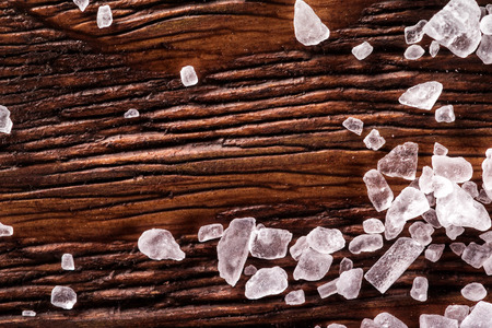 Macro image of white salt crystals at wooden table background.の写真素材