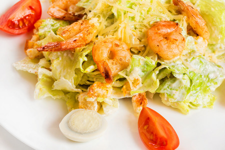 Closeup plate of caesar salad with shrimps isolated at white background.の写真素材