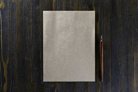 Mockup of blank vintage letterhead and pen at brown wooden background.の写真素材