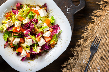 Fresh diet vegeterian salad decorated with herbs on wooden tray at table background.の写真素材