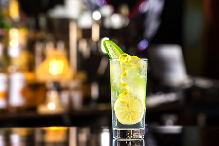 Glass of gin tonic cocktail decorated with cucumber at bat counter background.の写真素材