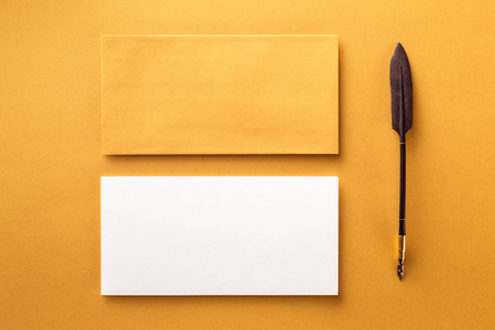 Mockup of envelope, blank white paper and vintage ink pen at golden paper background.の写真素材