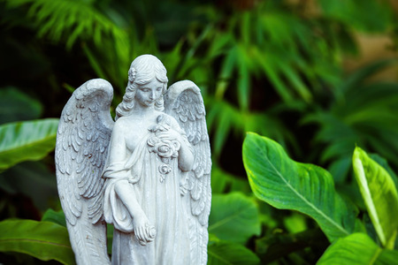 Marble statue of angel with closed eyes at green summer garden background.の写真素材