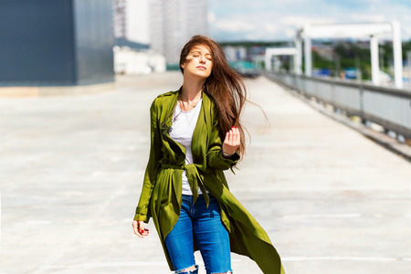 Young stylish female model is posing outdoors walking at urban background.の写真素材