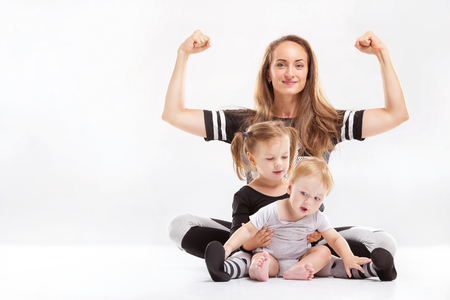 Portrait of healthy family of mother rising hands and playing children isolated at white background.の写真素材