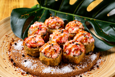 Closeup set of hot fried rolls with lava maki topping at wooden board background.の写真素材