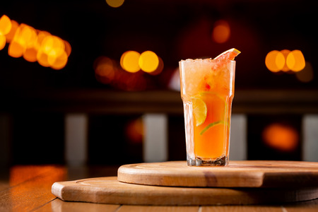 Glass of fresh orange juice with lemon, grapefruit and lime on a wooden board at dark blurred background.の写真素材