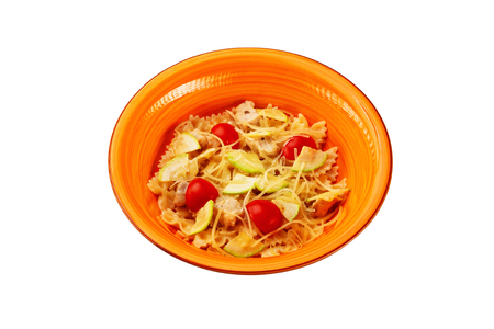 Closeup plate of tripolini italian pasta with tomato, cucumber and chicken isolated at white background.の写真素材