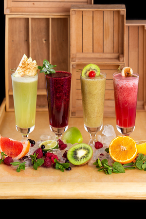 Group of fresh healthy fruit smoothies at wooden table background with ingredients around.の写真素材