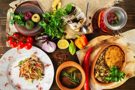 Top view image of traditional georgian lunch with various meals and ingredients at decorated wooden table background.