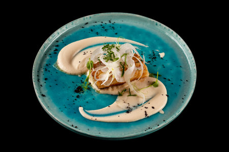 Plate of cod fillet with fennel served with cauliflower cream, ground olives and green basil...