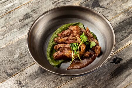 Pan of baked duck breast served with sauces at rustic wooden table background.の写真素材