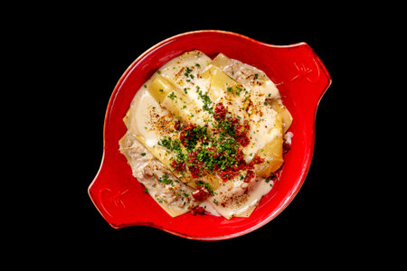 Top view plate of italian homemade lasagna with cheese, tomatoes and rabbit meat isolated at black background.の写真素材