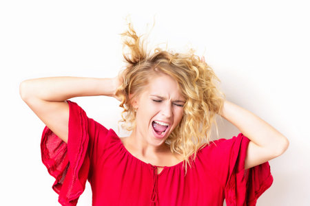 Portrait of stressed caucasian adult woman shouting and holding head isolated at white background.