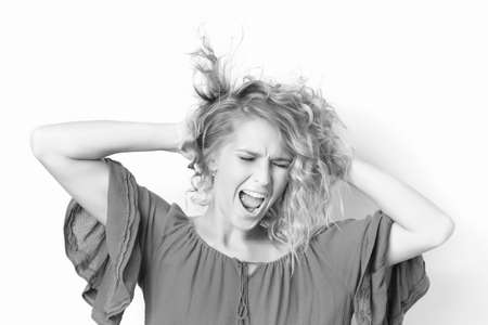 Black and white portrait of stressed caucasian adult woman shouting and holding head isolated at white background.の写真素材