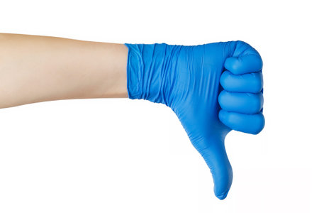 Female hand in blue latex protective glove showing negative gesture with thumn down isolated at...