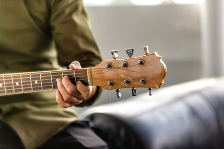 Male is playing guitar outdoors. Closeup image of musician hand holding strings.