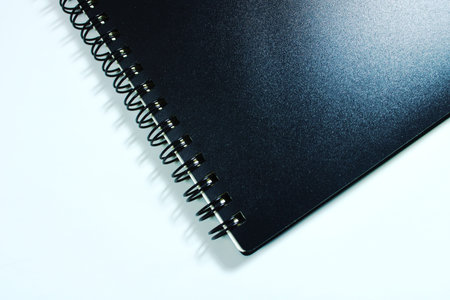 Close up view of black spiral notebook cover on white background. Minimalist stationery concept with copy space, ideal for education, office, planning, notes, business, and mockupの写真素材