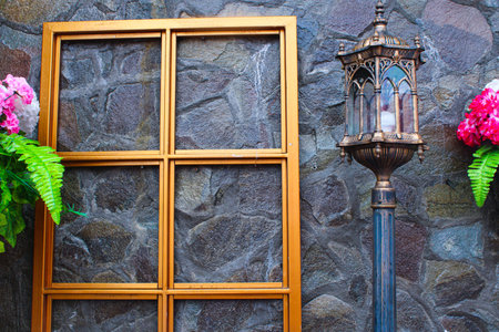 Vintage Gothic Lantern and Golden Window Frame Against Rustic Stone Wall. Classic Outdoor...