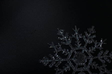 Glittering acrylic snowflake on a black background. Sparkling holiday ornament showcasing festive...