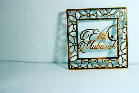 Gold Eid Mubarak decorative frame with Islamic geometric ornaments and crescent moon on light...