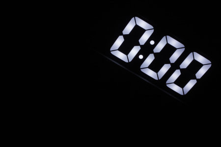 Minimalist Digital Clock Showing 0:00 Glowing in the Dark. Bright White LED Numbers on Black...