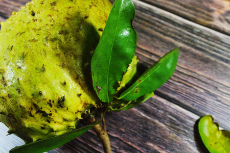 Fresh Soursop Fruit with Green Leaves on Rustic Wooden Background