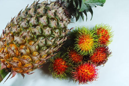 Fresh pineapple and ripe rambutan fruits isolated on white background