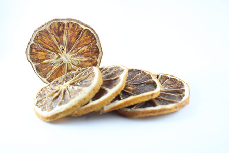 A tidy stack of dried lemon slices presented on a clean white background, highlighting their intricate patterns and natural textureの写真素材