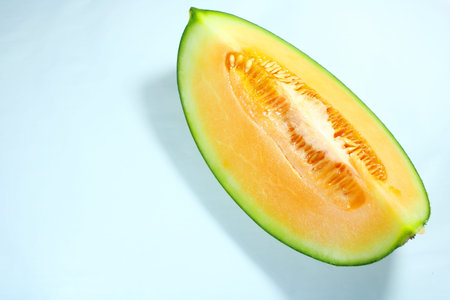 Fresh ripe melon slice with seeds and juicy orange flesh isolated on white background. Healthy...