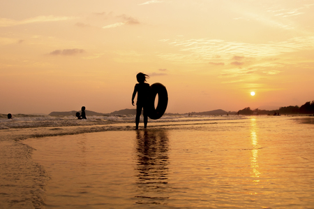 silhouette of girl standing on the beach at sunsetの写真素材