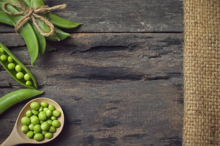 Green peas in wooden spoon on old wooden backgroundの写真素材