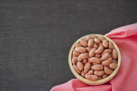 Raw peanuts or arachis in wooden bowl on table backgroundの写真素材