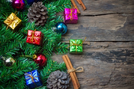 Fir tree branches, pine cones, colorful gift box and glass ball on wooden background for Christmas or New Year decoration backgroundの写真素材