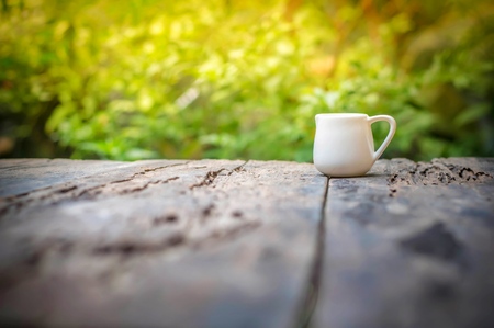 Small white pitcher on wooden table in the morningの写真素材