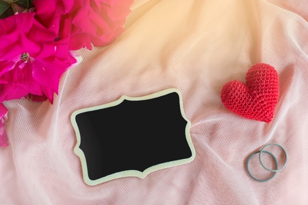 Red heart, Rings, rose and blackborad on pink fabric for Valentine's day or wedding backgroundの写真素材